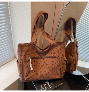 Brown corduroy tote bag detail with black heart bow prints and front zipper pocket