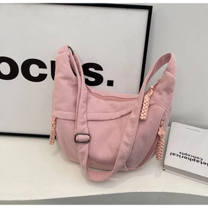 Détail du sac croissant en velours rose montrant la texture côtelée et le tire-zip tressé