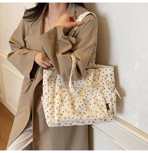 Detail view of corduroy tote bag with bow and heart prints worn with a trench coat