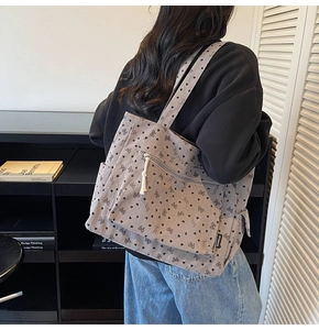 Detailed shot of grey corduroy tote bag featuring black bow and heart patterns