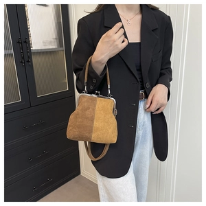 Detail of vintage brown suede doctor bag featuring contrast stitching and silver metal clasp
