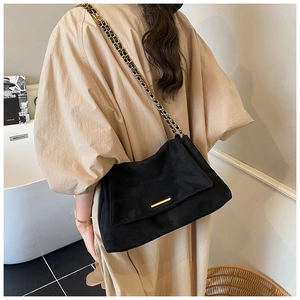 Détail du sac cabas en daim noir avec boucle dorée et bandoulière en chaîne cuir