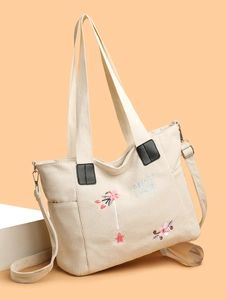 Detail of floral embroidery and corduroy texture on a versatile tote bag with side pocket