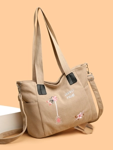 Close-up of beige corduroy tote bag with pink floral embroidery and reinforced handles