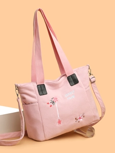 Detailed macro view of pink corduroy tote bag with floral embroidery and adjustable strap