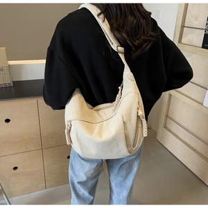 Détail du sac bandoulière en velours côtelé beige avec fermeture éclair tressée et sangle