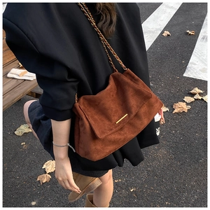 Photo de rue d'un sac bandoulière en daim marron avec chaîne dorée élégante