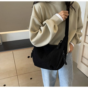Détail de la besace en velours côtelé noir avec zip tressé et sangle ajustable