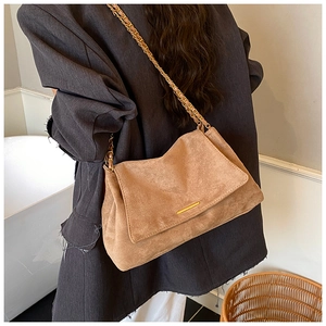 Détail du sac cabas en daim marron clair avec bandoulière chaîne dorée et cuir texturé