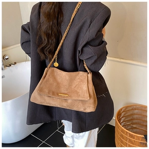 Gros plan détaillé du sac cabas en daim marron avec bandoulière chaîne dorée et boucle