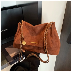 Détail d'un cabas en daim marron avec bandoulière chaîne dorée et pendentif métallique