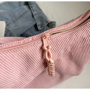 Détail du tissu en velours côtelé rose et fermeture éclair assortie d'un grand sac bandoulière