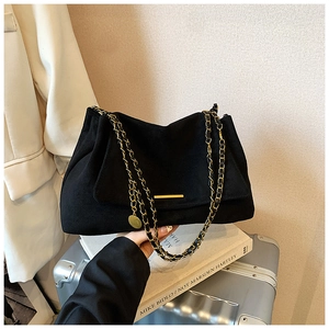 Détail du sac cabas en daim noir avec bandoulière en chaîne dorée et détails métalliques