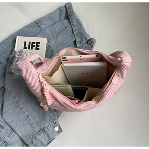 Détails de l'intérieur d'un sac bandoulière en velours côtelé rose avec compartiments