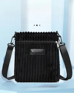 Detail of black corduroy shoulder bag showing leather label and fine texture