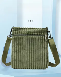 Detail of olive green corduroy shoulder bag with leather logo tag and metal zipper