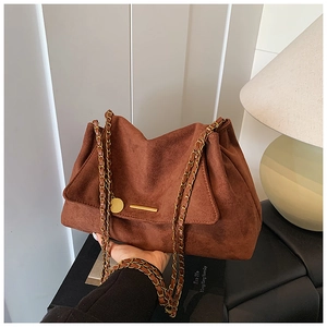 Détail du cabas en daim marron foncé avec bandoulière chaîne dorée et boucle métal