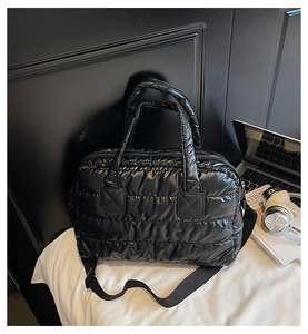 Detailed view of black quilted puffer gym bag with detachable strap in lifestyle setting