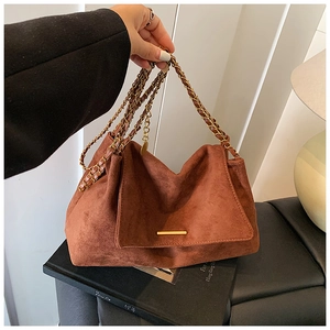 Détail d'un sac à bandoulière en daim marron avec chaîne dorée et garniture en métal