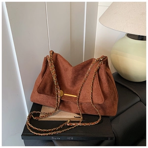 Détail du sac bandoulière en daim marron avec chaîne dorée et boucle métallique