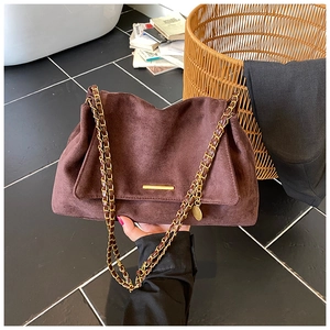 Détail d'un sac à main en daim marron foncé avec bandoulière chaîne dorée et garniture