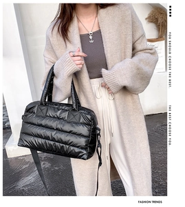 Detail of black quilted puffer tote showing padded texture and detachable strap