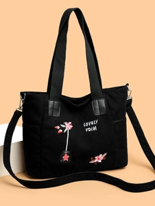 Detail of floral embroidery and corduroy texture on black canvas tote bag