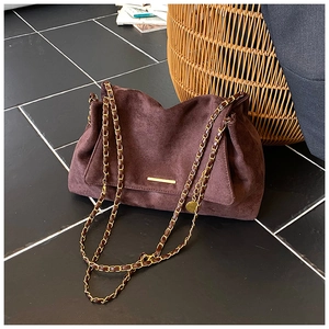 Détail du sac cabas en daim marron foncé avec chaîne dorée et texture vintage