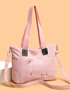 Detail of pink corduroy tote bag featuring floral embroidery and leather buckle straps