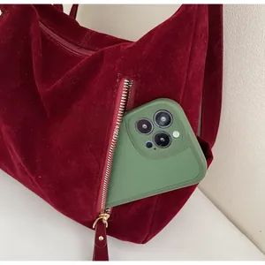 Macro shot of side zipper pocket on burgundy suede tote bag with phone inside