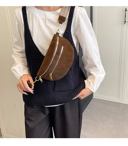 Detail of brown suede saddle bag with woven geometric strap worn by a model
