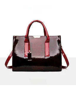 Detail van donkerrode laklederen shopper met slangenmotief en metalen accessoires