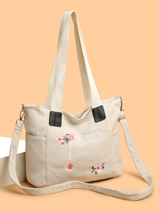 Detailed close-up of corduroy tote bag featuring floral embroidery and sturdy handles
