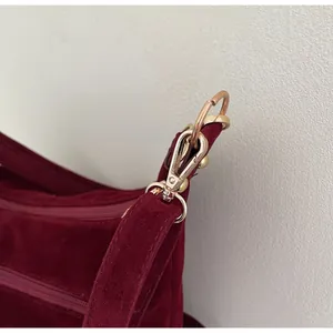 Detail of burgundy suede tote with premium golden metal lobster clasp and strap buckle