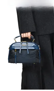Détail du sac à main en cuir verni bleu et cuir embossé crocodile noir avec poignée métal