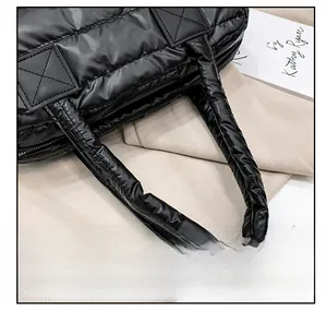 Detail of wide quilted handle and soft padded nylon texture on the black tote bag