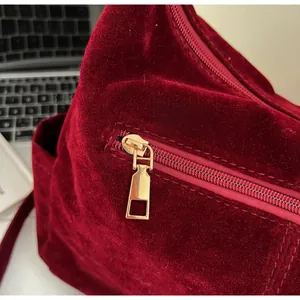 Detail of smooth gold metal zipper on burgundy velvet tote bag for women
