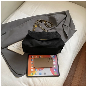 Détail d'un sac cabas noir en daim à chaîne montrant la grande capacité pour un ordinateur