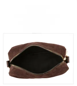 Detail of dark brown suede camera bag featuring golden zipper and black lining interior