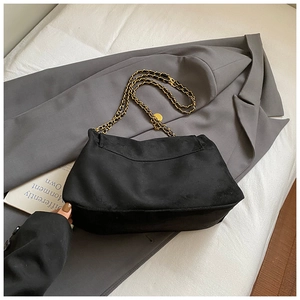 Détail du sac cabas en daim noir avec bandoulière en chaîne dorée et cuir tressé