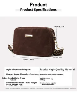 Close-up detail of brown suede crossbody bag with gold hardware and geometric jacquard strap