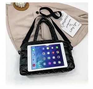 Detailed top view of a black quilted tote bag shown next to a tablet for size reference