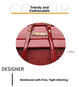 Gros plan du sac carré en cuir verni rouge montrant les coutures et le logo doré
