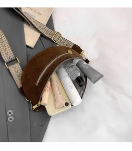 Detailed view of spacious interior in dark brown suede saddle bag with jacquard strap