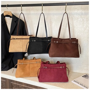 Détail des sacs fourre-tout en daim beige, noir, marron et rouge sur des crochets