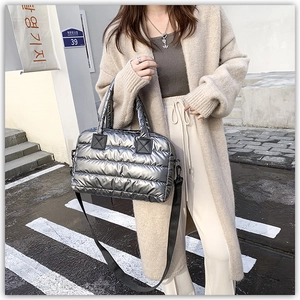 Detail of silver quilted puffer bag featuring high-shine metallic finish and fabric straps