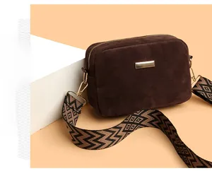 Detail of dark brown suede crossbody bag with geometric jacquard woven strap and gold metal hardware