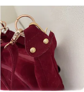 Detail of burgundy velvet tote bag featuring polished gold hardware and decorative rivets