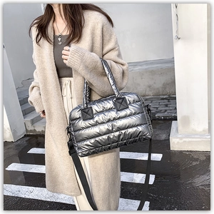 Close-up of metallic silver quilted tote bag featuring black reinforced leather accents