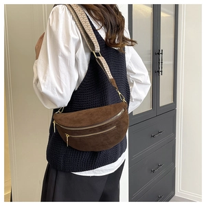 Detail of dark brown suede crescent chest bag with jacquard strap and gold hardware